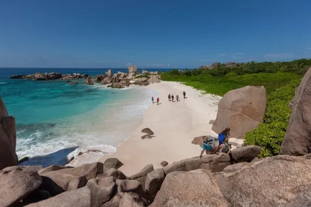 Secluded tropical beach ain Seychelles with clear turquoise waters, white sandy shores, and large granite boulders, perfect for relaxing and exploring nature.