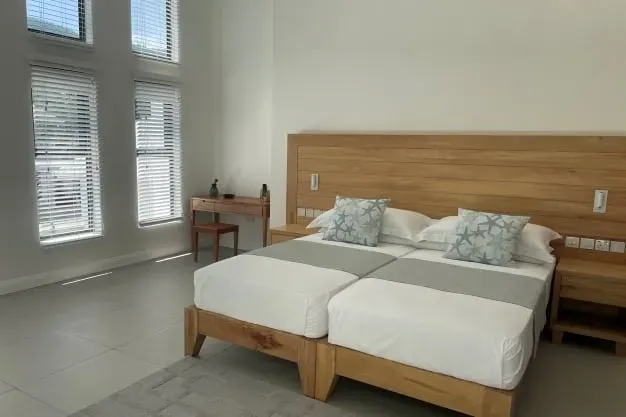 Luxurious beachfront villa bedroom with modern decor, wooden furniture, and natural light, ideal for a relaxing vacation at Lyla Beach Villa.