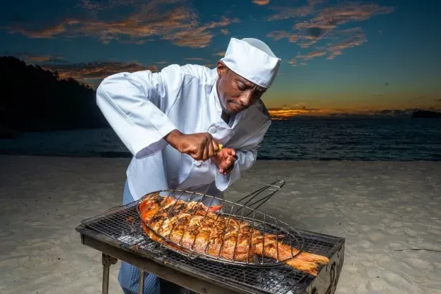 Grilling fish on the beach, highlighting outdoor dining and beachside relaxation.