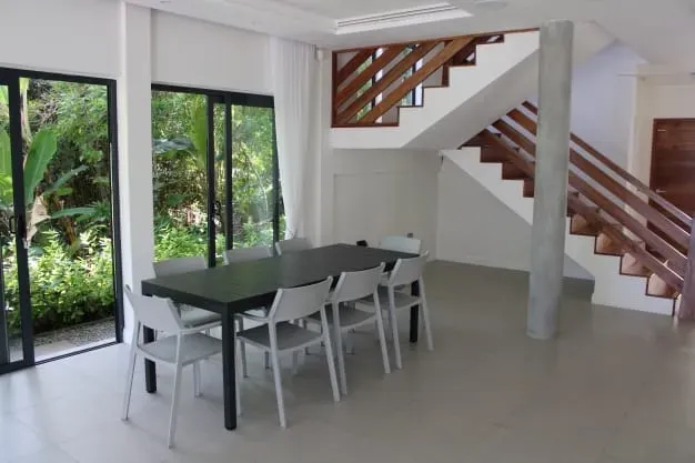 Spacious dining area with modern furniture overlooking lush greenery at Lyla Beach Villa. Perfect for relaxing and enjoying scenic views in a luxurious tropical vacation rental.
