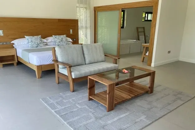 Modern luxurious main bedroom suite at Lyla Beach Villa featuring a cozy seating area, stylish wooden furniture, and elegant decor, perfect for a relaxing beachside vacation stay.