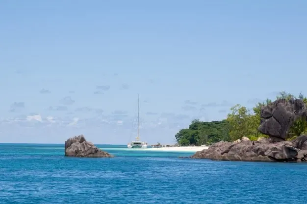 Lyla Beach Villa sSshoreline, tropical greenery, and a luxury sailboat, perfect for a relaxing Seychelles vacation.