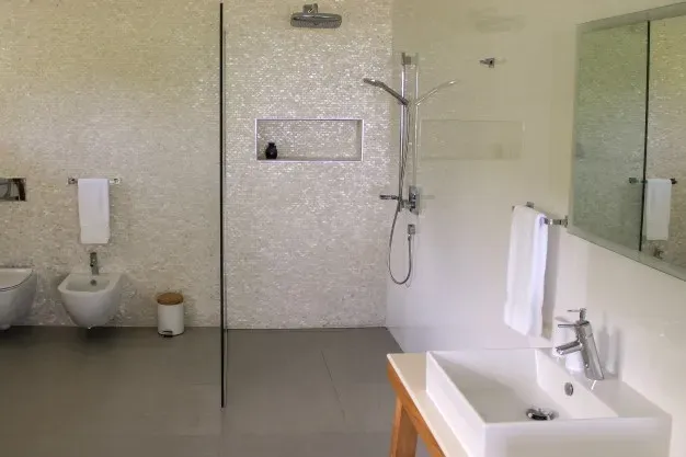 Spacious modern bathroom with walk-in shower, white fixtures, and elegant tiling at Lyla Beach Villa for a luxurious tropical getaway.